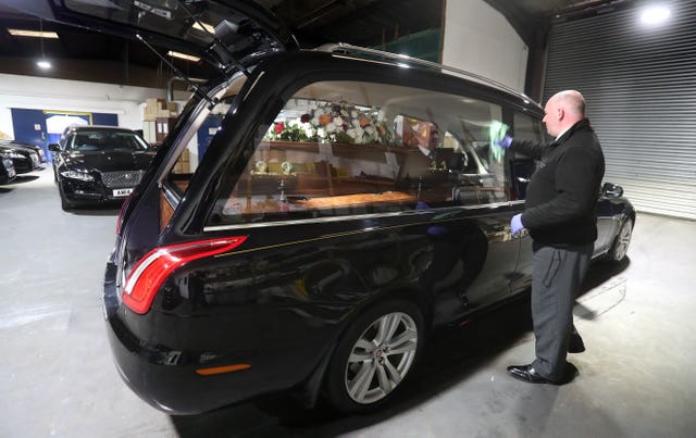 Christopher Bradley from Anderson Maguire Funeral Directors polishes a hearse at their offices in Glasgow (Andrew Milligan/PA)
