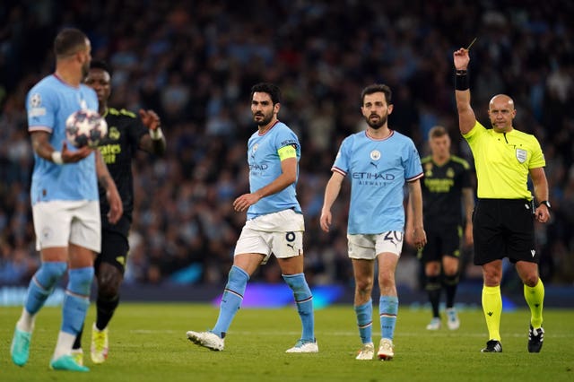 Manchester City’s Ilkay Gundogan, centre, is shown a yellow card by referee Szymon Marciniak, right, during the Champions League semi-final second leg against Real Madrid