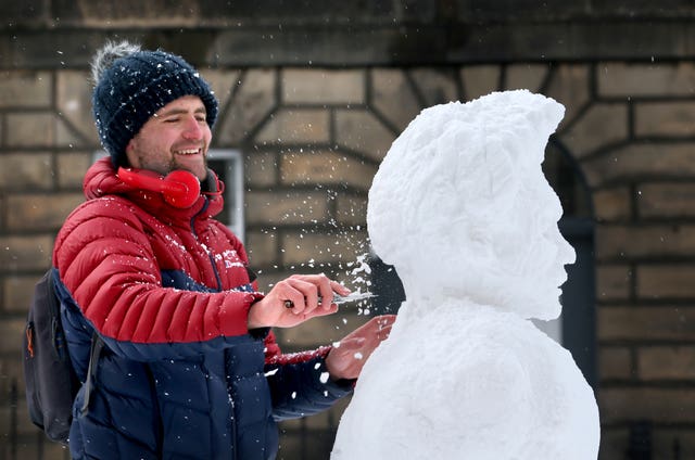 Artist Tom Wigmore, from Leith, makes a ‘snow-woman’ in the street in Edinburgh (Jane Barlow/PA)