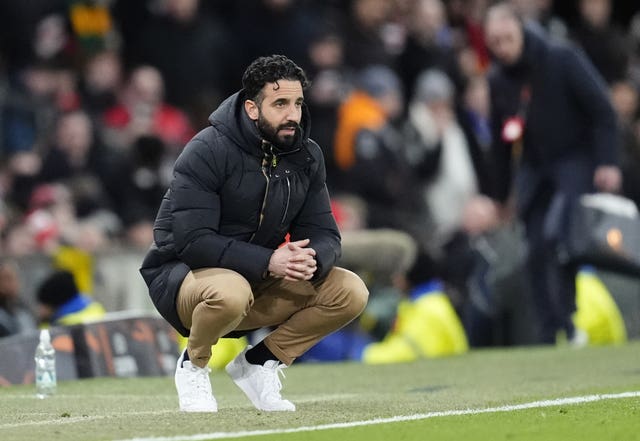 Manchester United manager Ruben Amorim crouches on the touchline