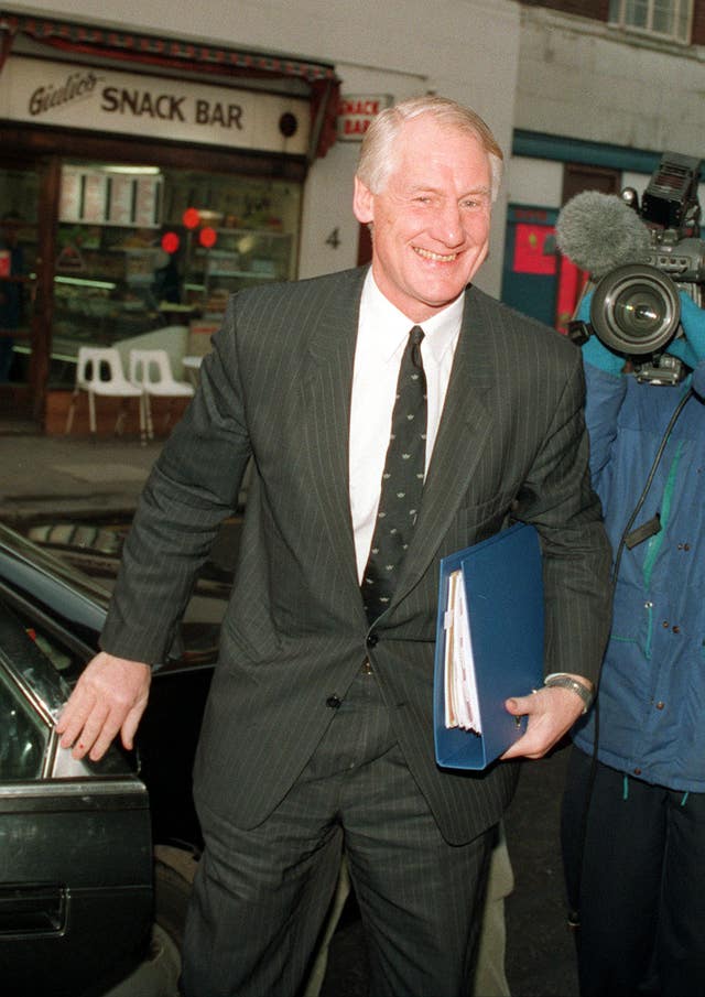 Sir Robin Butler stepping out of a car carrying a file 