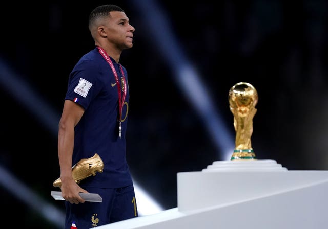Kylian Mbappe walks past the World Cup trophy with his runner-up medal and Golden Boot trophy