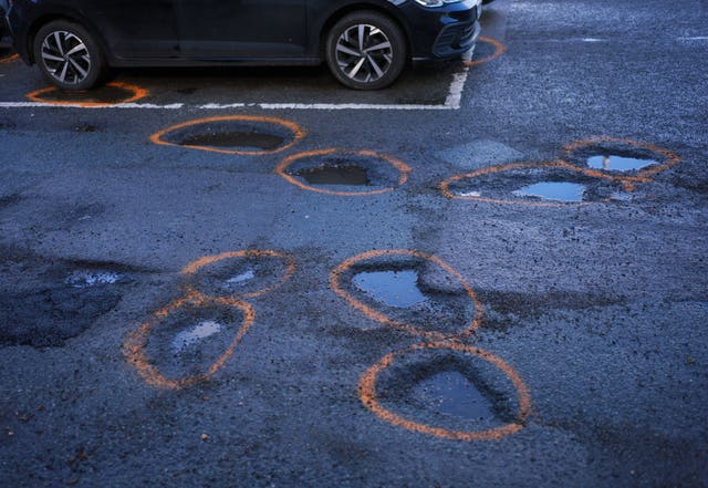 Potholes with orange spray paint around them after being earmarked for repair