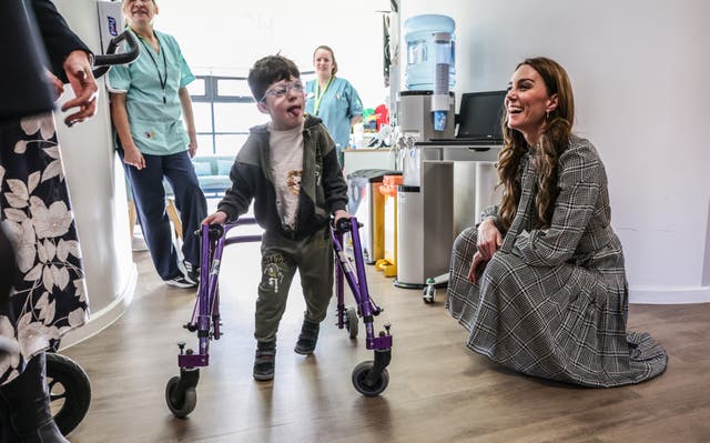 Princess of Wales crouches down to talk to a boy with a walker