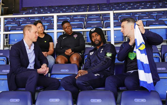 The Prince of Wales (left) is presented with a shirt by Grenfell survivors and bereaved during a visit to Loftus Road, the home of Queens Park Rangers in 2023
