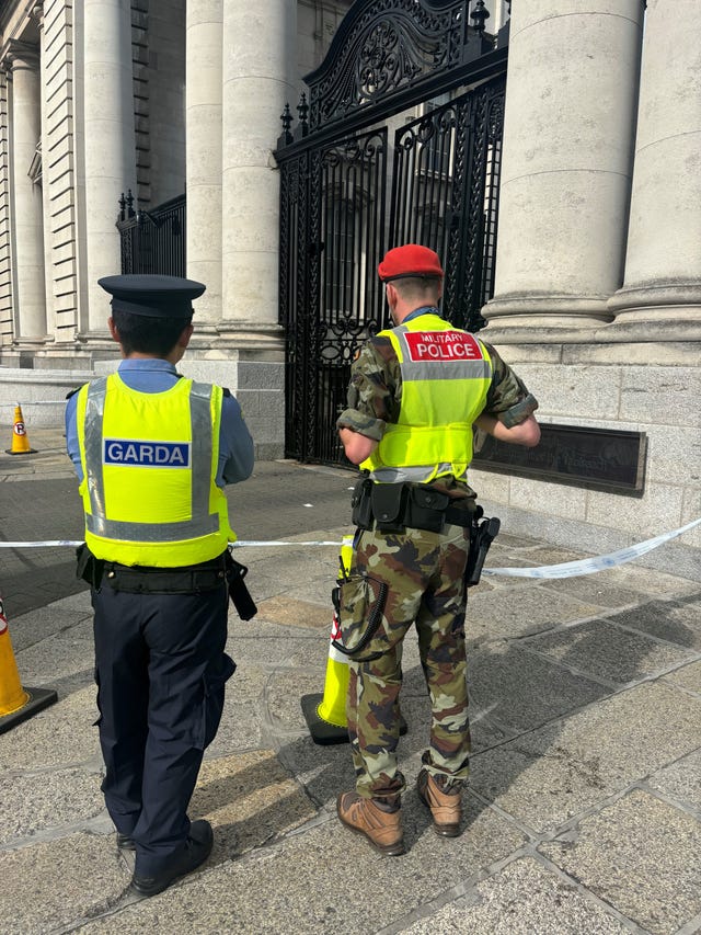 A Garda officer and a military police officer look at damage caused to gates outside Government Buildings in Merrion Street, Dublin