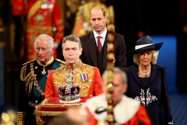 Charles, William and Camilla walking through the Horse of Lords behind the Imperial State Crown