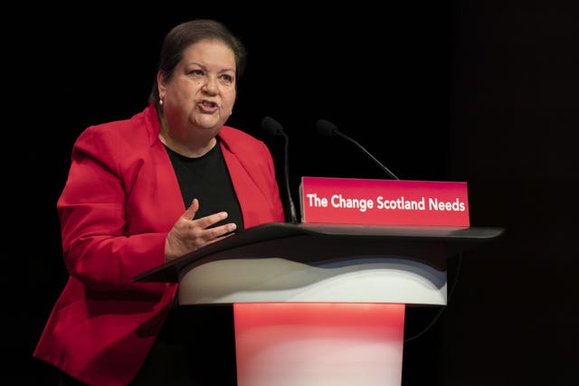 Jackie Baillie giving a speech behind a podium that says 'the change Scotland needs' on the front of it