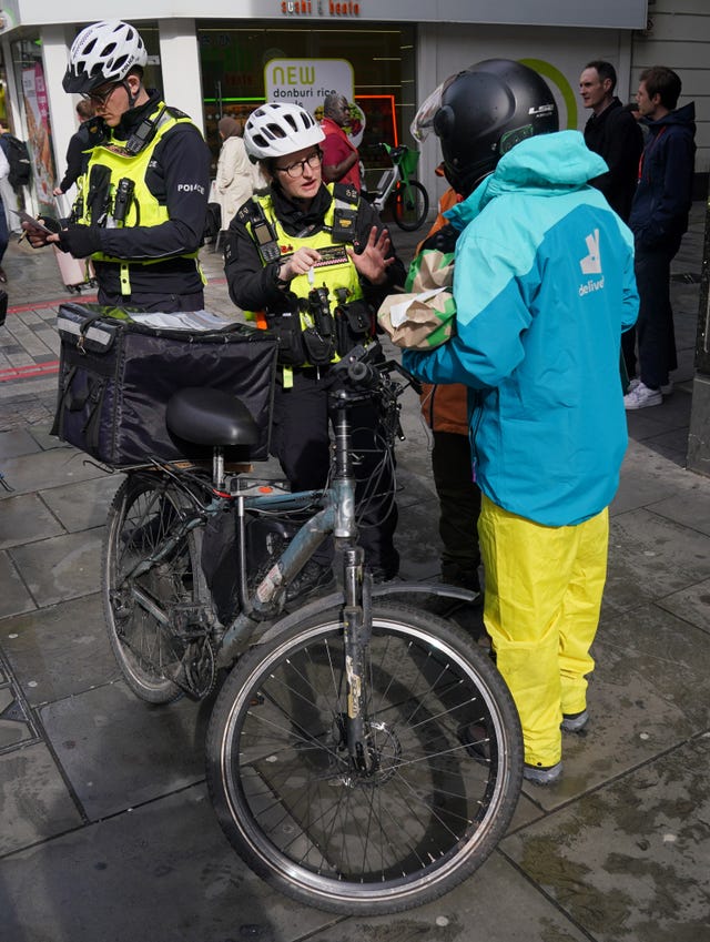 Officers from City of London Police talk to a food delivery worker