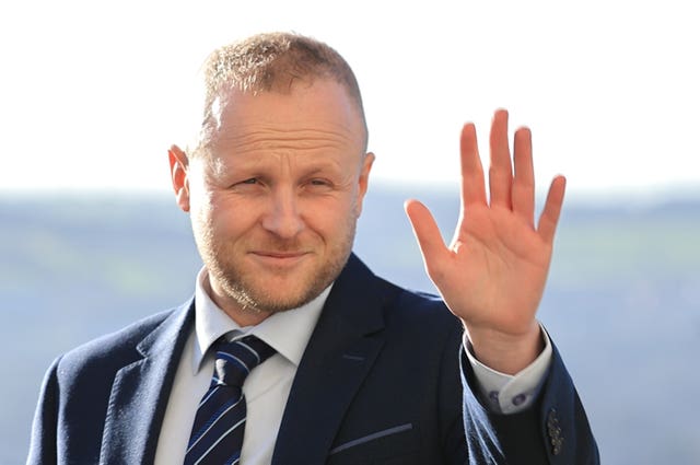 A close-up of Jamie Bryson waving