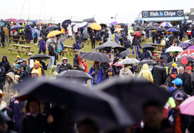 People wearing waterproof coats and sheltering under umbrellas at Silverstone