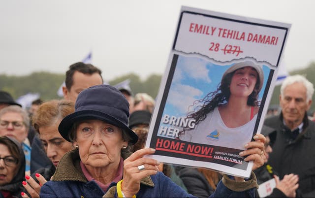 A woman standing in a crowd holding a poster of Emily Damari