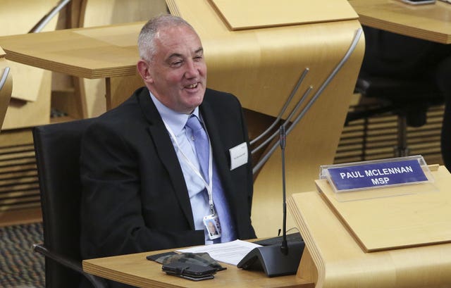 Paul McLennan smiling while seated in the Holyrood chamber