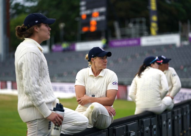 Katherine Brunt and her England team-mates sit on the boundary fence at the end of a day's play against India