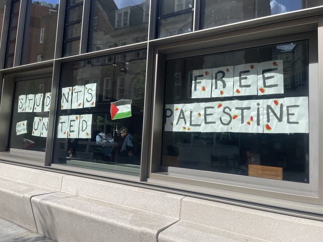 Signs stuck to a window read 'Students united' and 'Free Palestine' and show the Palestine flag