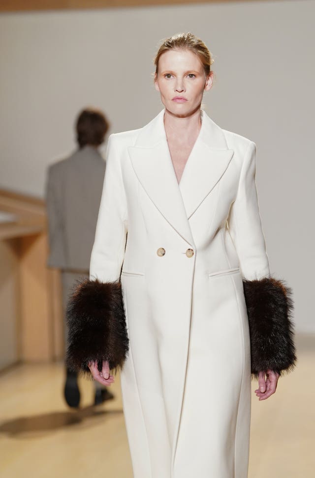 Lara Stone on the catwalk in a white coat with black furry sleeves