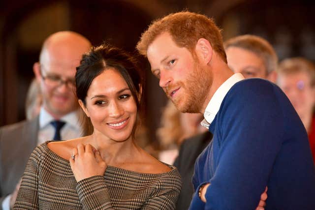Prince Harry whispers to Meghan Markle as they watch a dance performance in Cardiff (Ben Birchall/PA)