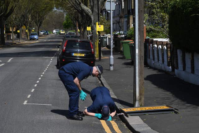 Police search a drain in Chestnut Avenue after the fatal stabbing (Stefan Rousseau/PA)