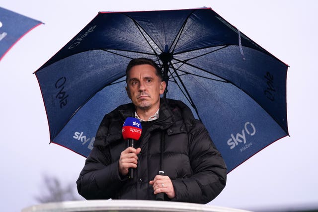 Gary Neville holding an umbrella and microphone