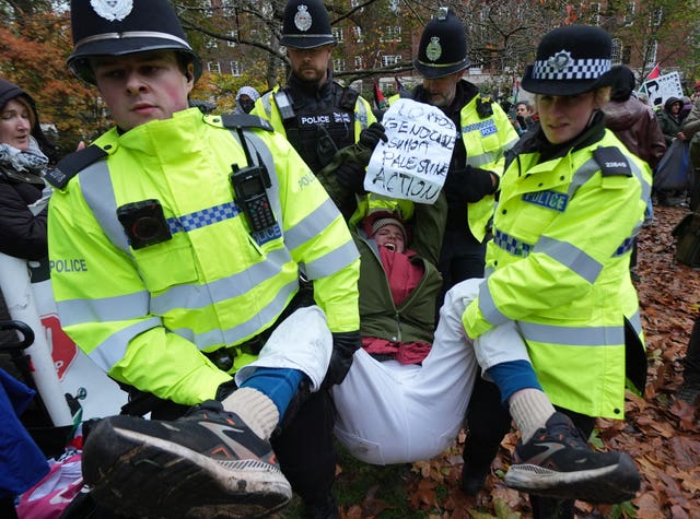 Police carrying a protester holding a banner