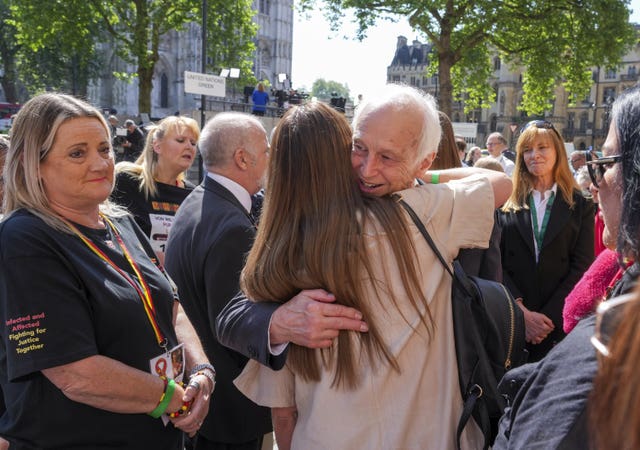 Chairman of the infected blood inquiry Sir Brian Langstaff with victims and campaigners outside Central Hall in Westminster, London, after the publication of the Inquiry report 