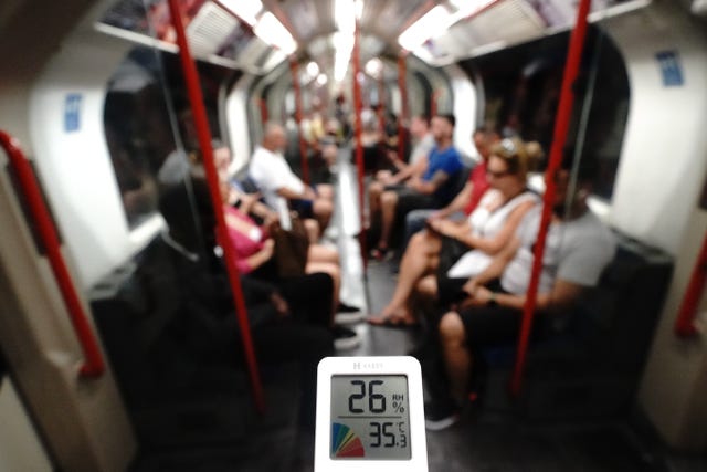 A person holds a thermometer on the Central line of the London Underground