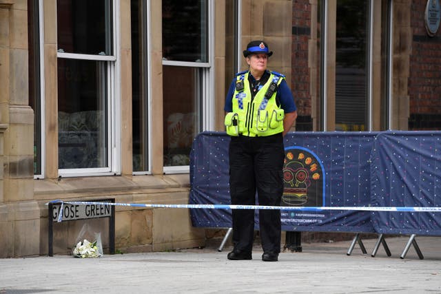 A PCSO stands alongside a floral tribute at the scene in Railway Street in the Goose Green area of Altrincham, Trafford, where 31-year-old Rico Burton, the cousin of heavyweight boxing champion Tyson Fury, died following an alleged stabbing incident 