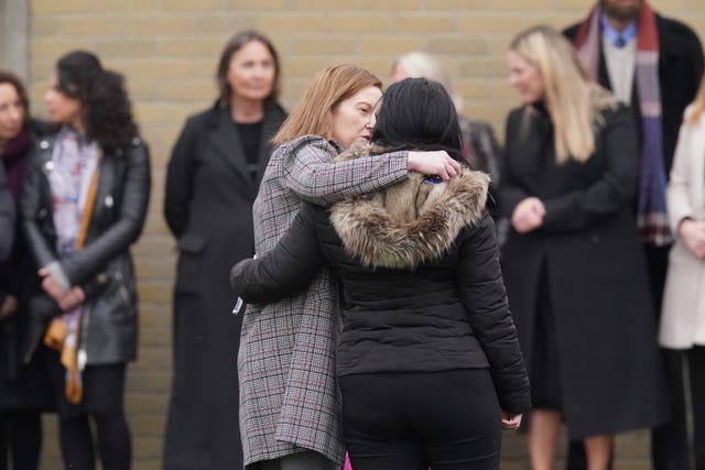 Mourners comfort each other outside the church