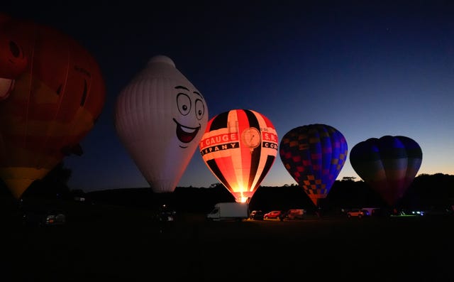 Hot air balloons take part in a night glow during a preview for Icons of the Sky