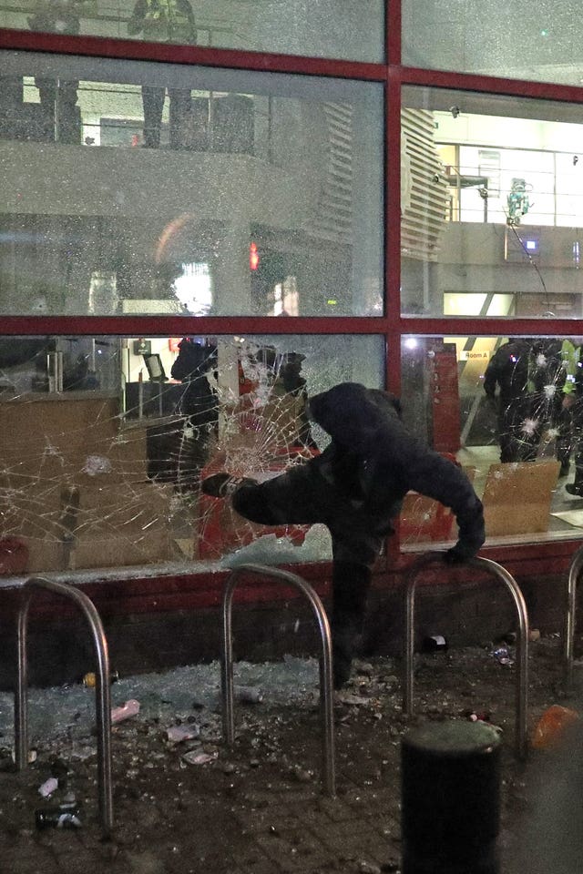 A protester kicks a smashed Bridewell police station window in Bristol