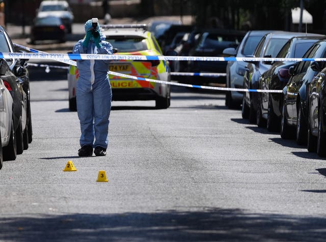 Police officers in forensic suits at the scene of the shooting on Willington Road in Clapham 