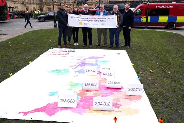 Labour MP Grahame Morris, fourth from left, joins campaigners unveiling a giant map outside the Houses of Parliament in Westminster, London, showing the numbers of voters at risk of being turned away from polling stations because of the voter ID rollout