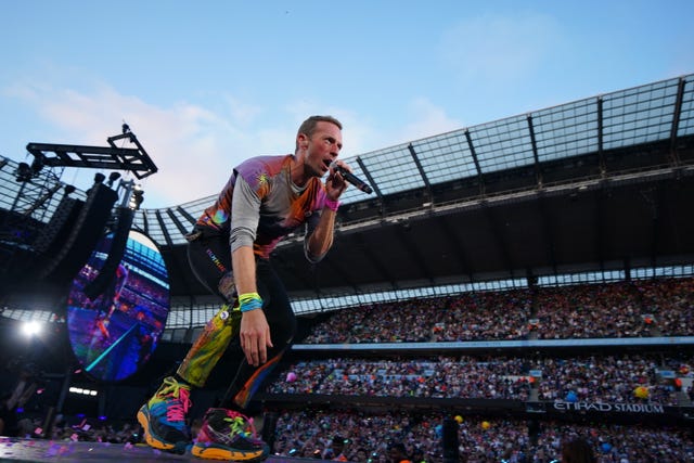 Chris Martin of Coldplay on stage in front of a stadium audience
