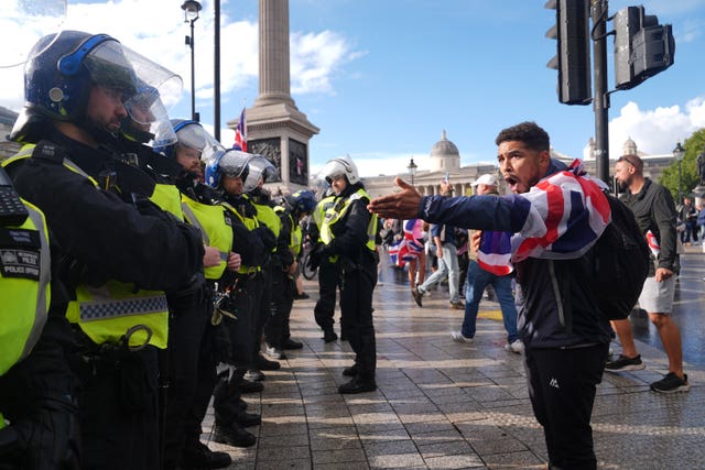 Police officers in a line with a protester wearing a British flag shouting at them