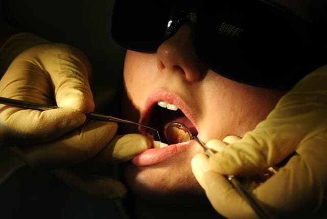 A dentist examines a patient's mouth