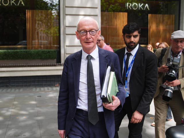 Cabinet minister Pat McFadden  holding a folder and walking in front of other men