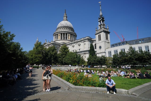 People enjoy the warm weather in Festival Gardens at St Paul’s Cathedral in London as the heatwave continues in the UK