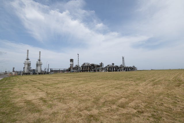 A view of a gas terminal in the distance, with grassland in the foreground