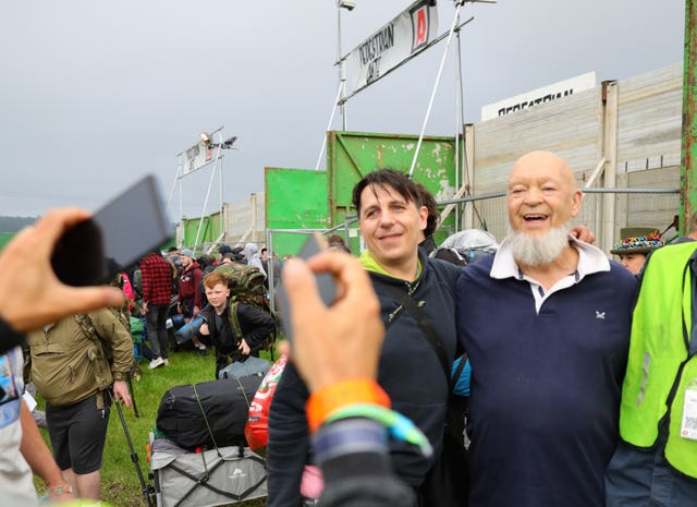 Festival organiser Michael Eavis takes pictures with fans as people arrive on the first day of the Glastonbury Festival at Worthy Farm in Somerset
