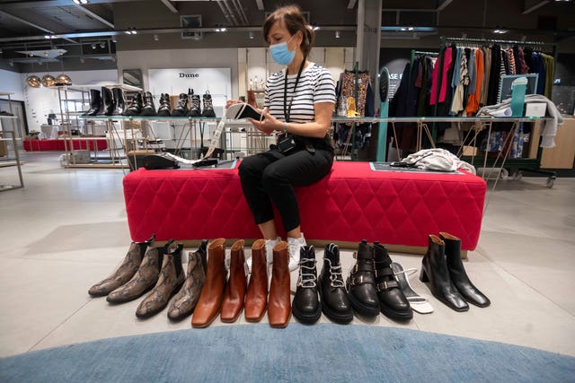A staff member cleaning shoes at the John Lewis White City store ahead of reopening (Paul Grover/PA)