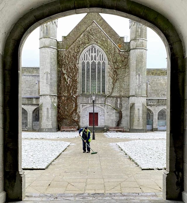 A staff member at the University of Galway clears snow from pathways