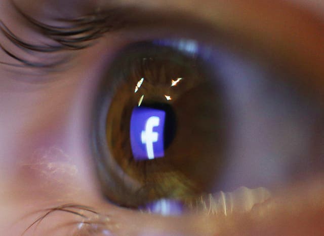 The logo of social media and networking site Facebook is reflected in an eye, in London