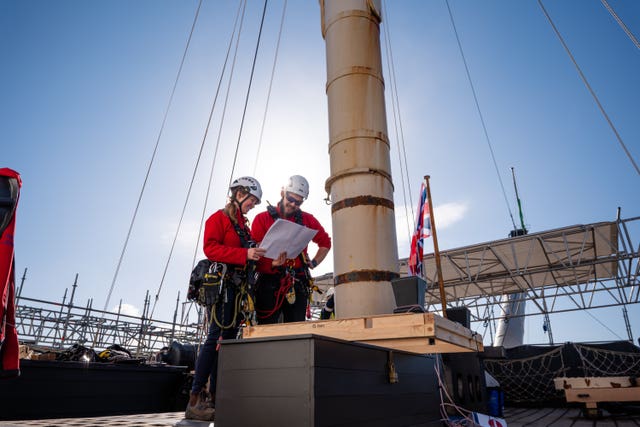 Two people in red at the bottom of a mast
