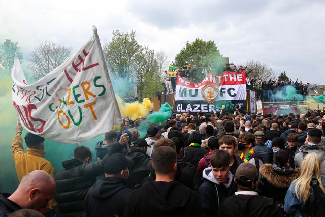 Manchester United fans hold up banners as they protest against the ownership of the Glazer family