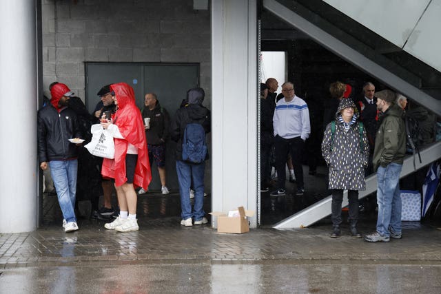 Spectators shelter from the rain outside the Emirates Old Trafford stadium, Manchester ahead of the Vitality International T20 match between England and Australia