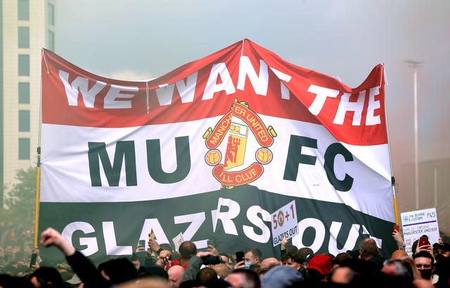 Fans hold up a banner as they protest against the Glazer family