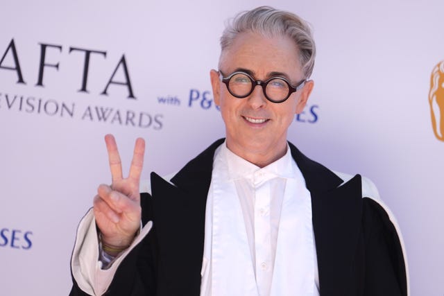 Alan Cumming giving a peace sign