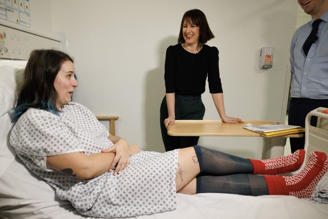 Chancellor of the Exchequer Rachel Reeves talking to a woman sat on a bed at a hospital