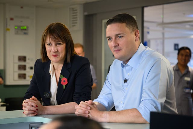 Wes Streeting and Rachel Reeves, both with sleeves rolled up, sit in a hospital