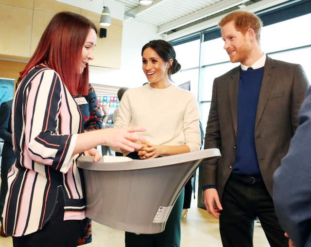 Sinead Murphy from Shnuggle baby products shows Prince Harry and Meghan Markle a baby bath during a visit to Catalyst Inc science park in Belfast (Niall Carson/PA)